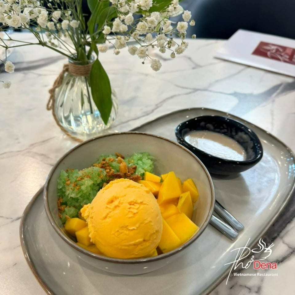Mango sticky rice dessert with green rice, mango ice cream, and fresh mango chunks at Pho Dena.