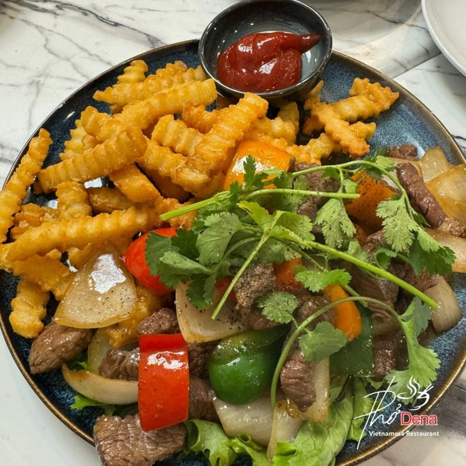 Shaking beef with bell peppers, onions, and cilantro, served with crinkle-cut fries and ketchup.