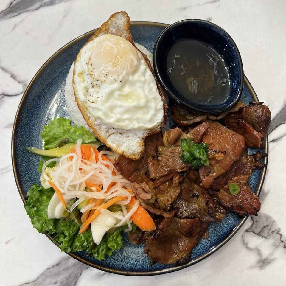 Pho Dena's Vietnamese grilled pork with a fried egg, rice, pickled vegetables, and dipping sauce.